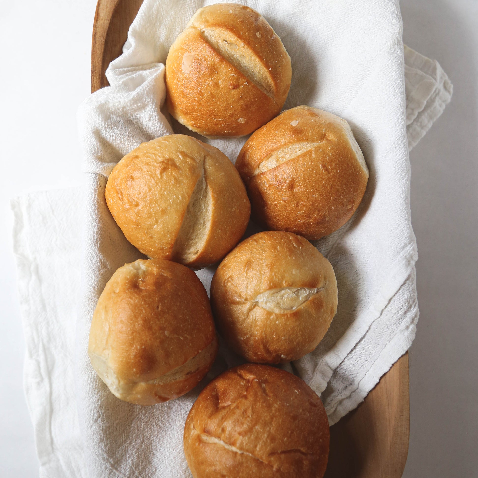 Bread rolls in a wooden basket with a white cloth